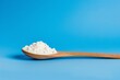white powder on a wooden spoon on blue background