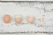 Eggs and egg shells on light, wooden background, top view, simple easter decoration.
