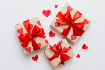 Top view photo of valentine day decorations gift box with red ribbon bow on colored background. Holiday gift boxes with top view