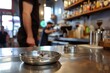 stainless steel ashtray on bar counter with barista in background