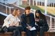 © standret - With notepad. Three young students are outside the university outdoors