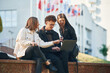 © standret - Sitting and using laptop. Three young students are outside the university outdoors