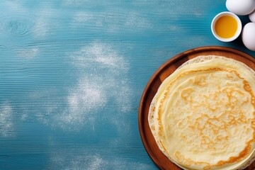 Wall Mural - 
Traditional thin crepes pancakes, on wooden blue table with ingredients for cooking - flour, eggs, butter, top view copy space