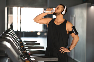 Canvas Print - Handsome Young Male Athlete Drinking Water While Training At Treadmill At Gym,