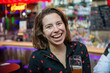 Young woman enjoying an alcoholic drink in a popular bar. Laughing having fun with friends