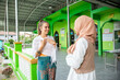 © Connect Images - Two young female friends one wearing a hijab, shows her friend how muslim women greet each other.