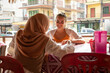 © Connect Images - Two young women one wearing a Hijab   sitting together in a cafe restaurant in a rural town in Thailand