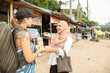 © Connect Images - Two young women one wearing a Hijab greet each other in a rural town in Thailand