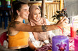 © Connect Images - Two young female friends one wearing a Hijab sit together in a restaurant playing with their phones and taking selfies.