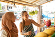 © Connect Images - Two young women one wearing a Hijab buying dragon fruit in a rural town in Thailand