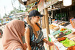 © Connect Images - Two young women one wearing a Hijab buying street food in a rural town in Thailand