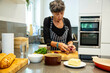 © Connect Images - A woman prepares food in her modern kitchen