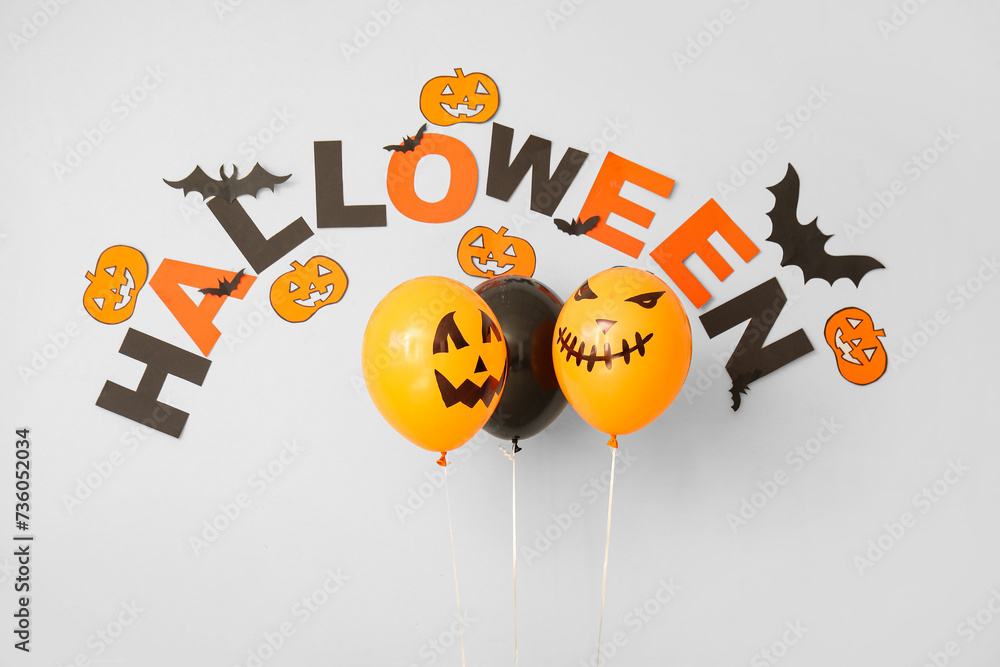 Word HALLOWEEN with balloons and paper decor on white background