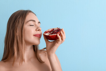 Poster - Young woman with pomegranate on blue background, closeup