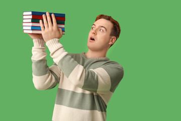 Wall Mural - Emotional man holding stack of books on green background