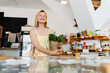 © nataliaderiabina - Smiling woman buying organic food and eco products in sustainable plastic free store. Happy female customer shopping at local grocery shop.