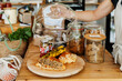 © nataliaderiabina - Seller in apron showing freshly croissants and healthy vegan bakery products in zero waste shop.