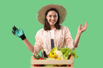 Wall Mural - Female farmer with box of fresh vegetables on green background