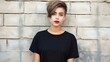 Fashionable girl with red lipstick and short hair and dressed in a black T-shirt, standing on the cement wall background