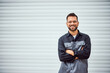 © bnenin - Portrait of a smiling mechanic man, holding his hands crossed, looking and posing for the camera in front of his garage.