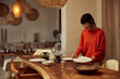 © bnenin - A smiling Asian woman serving a table for dinner, holding a plate.