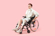 Injured young man after accident in wheelchair on pink background