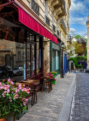 Wall Mural - Cozy street with tables of cafe in quarter Montmartre in Paris, France. Cozy cityscape of Paris. Architecture and landmarks of Paris.