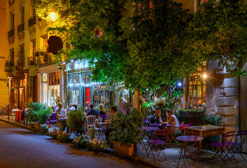 Wall Mural - Cozy street with tables of cafe in Paris, France. Night cityscape of Paris. Architecture and landmarks of Paris.