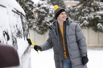 Canvas Print - Man cleaning snow from car window outdoors