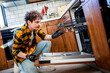 © Mediteraneo - Latino man fixing dishwasher in the kitchen.