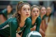 © familymedia - A team of young women in matching green uniforms, their determined faces reflecting their passion for the sport, engage in a thrilling indoor volleyball game, showcasing their physical fitness and at