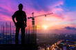 silhouette of engineer with protective hat on building site, construction site in evening, city ​​view sunset