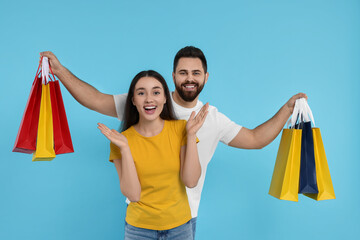 Wall Mural - Excited couple with shopping bags on light blue background