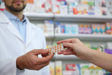 Wall Mural - Professional pharmacist giving pills to customer in drugstore, closeup