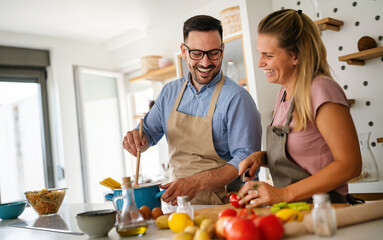 Wall Mural - Attractive couple is cooking together organic healthy food in kitchen.