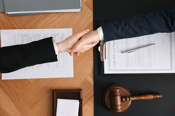 Canvas Print - Notary shaking hands with client at wooden table, top view