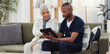 © Wesley/peopleimages.com - Old woman, man and tablet, caregiver with patient for healthcare and medical information or help with social media. Support, African nurse for elderly care and tech, telehealth and how to work app