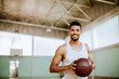 © Marko Geber - Smiling young man with a basketball in indoor court
