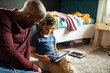 © Marko Geber - Boy using tablet with father next to him at home