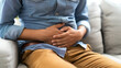 © Lansk - Gastroenterologist examining patient with stomach pain on couch in clinic, closeup