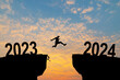 © Philip - Man jumping on cliff 2024 over the precipice with stones at amazing sunset. New Year's concept. 2023 falls into the abyss. Welcome 2024. People enters the year 2024, creative idea.