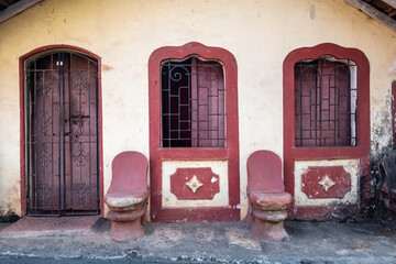 Vintage stone peaches on the porch of an old Portuguese era house with arched doors and windows in the old town of Madgaon.