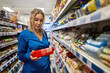 © M-Production - A woman in a blue dress chooses cookies in a store.