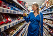 © M-Production - A woman in a blue dress chooses sweets in a store.