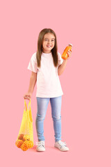 Wall Mural - Cute little girl with juice and string bag of oranges on color background