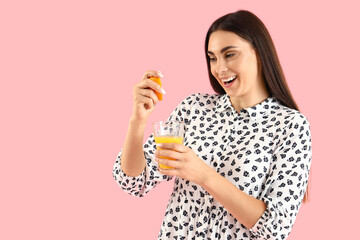 Sticker - Young woman with glass of juice and orange on pink background