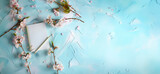 Fototapeta  - cahier ou bloc-notes, mock-up, avec des branches de fleurs de cerisier autour, sur un fond texturé à la peinture, bleu clair et blanc avec espace négatif pour texte, copyspace