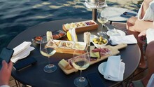 Group Of People Having Aperitif Time On The Swimming Pool Side, Friends Sitting At The Table And Tasting Delicious Traditional Italian Aperitif, Goblets With Refreshing White Wine, Salami And Cheese