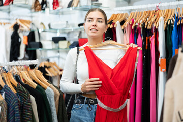 Canvas Print - Young woman buyer chooses evening dress in clothing store..