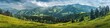 Panoramic view of a hilly landscape with lush green meadows and forests.